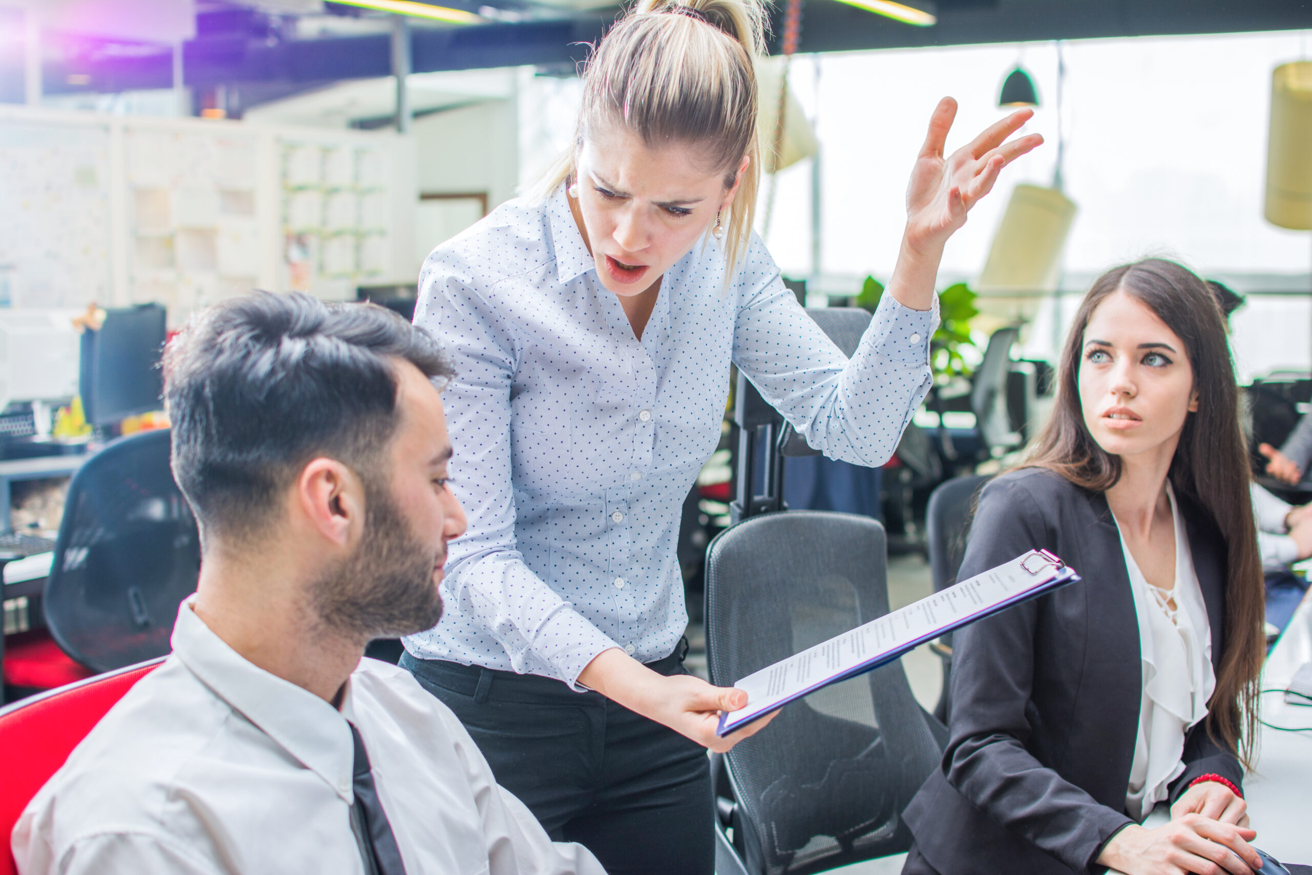 Difficult tech boss concept. Angry ponytailed woman shouting at work colleague in office.