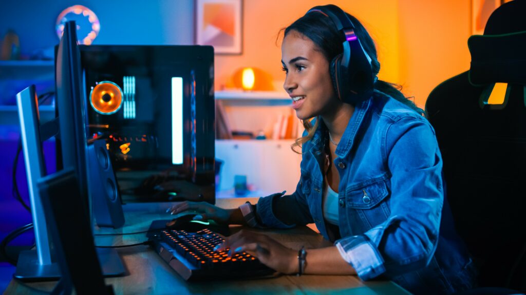 Kubernetes skill concept. Excited young woman wearing headphones at desktop monitor and keyboard.