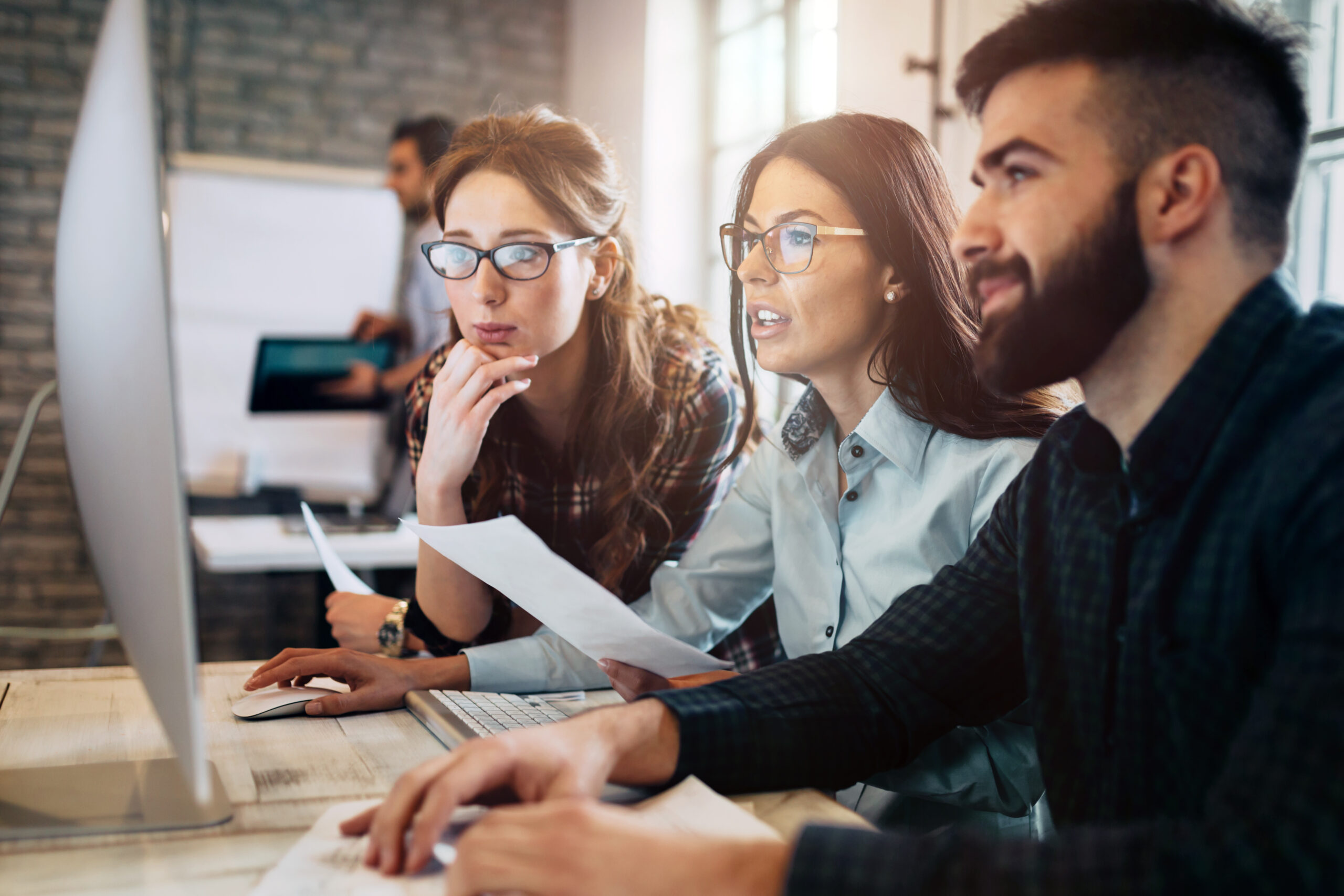 Kubernetes jobs concept. Company employees sitting around desktop PC monitor